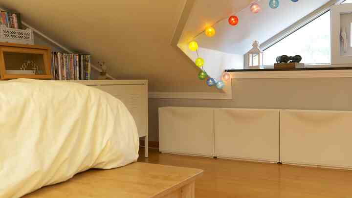 Cozy natural-toned 6-tatami bedroom featuring a bed beneath a slanted ceiling and white storage cabinets