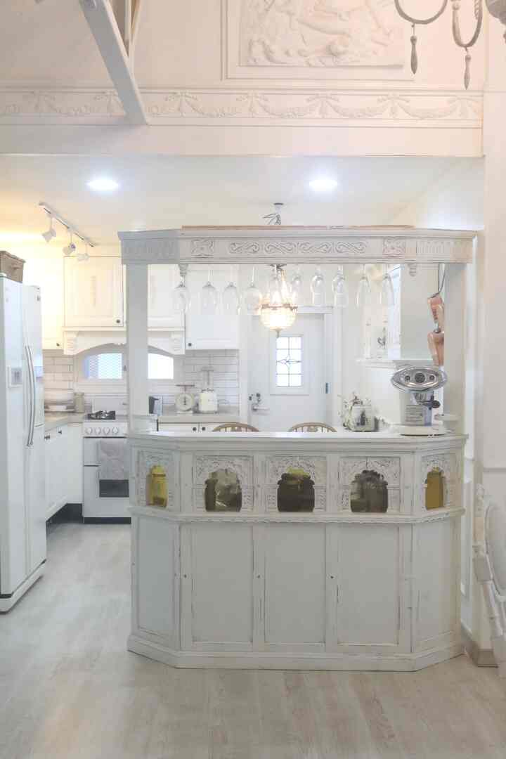 White-toned French country style kitchen featuring home bar with wine glasses in a classic atmosphere