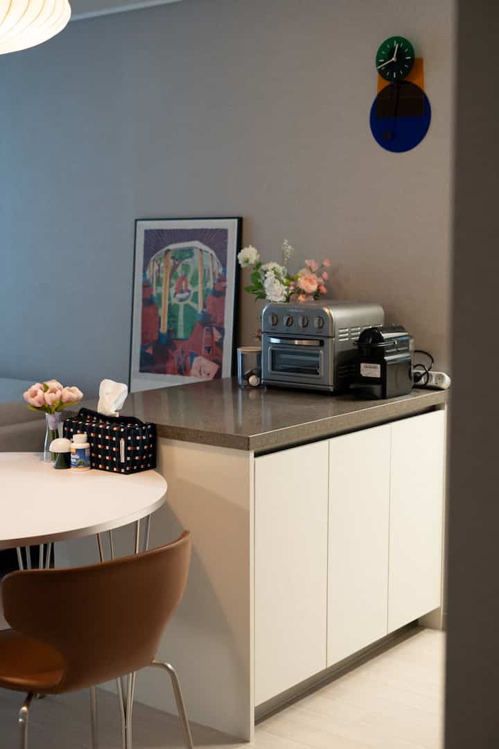 Beige-toned kitchen and dining room featuring capsule coffee machine and air fryer in a minimal style interior