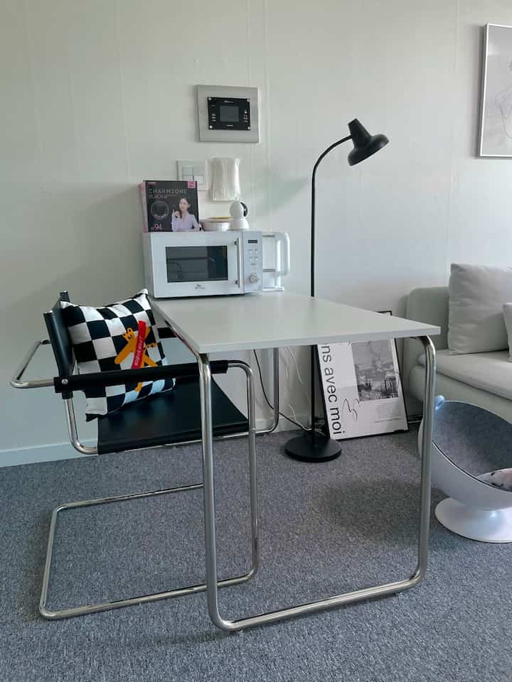 ホワイトとブラックのトーンが特徴のコンパクトなキッチンスペース、モダンなスチール製テーブルと椅子が置かれた食事兼作業スペース