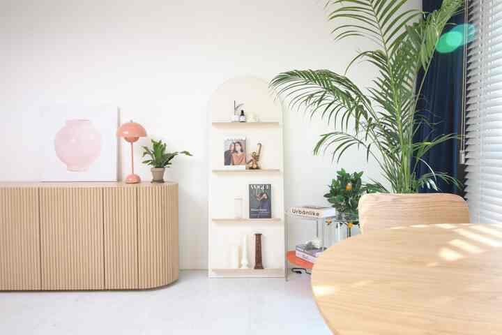 明るいウッドトーンとネイビーの遮光カーテンが調和したリビング、棚やマガジンラック、ダイニングテーブル、緑の植物が配置された雰囲気のあるインテリア