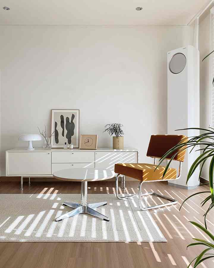 Bright modern living room in white and orange tones featuring a round table and lounge chair