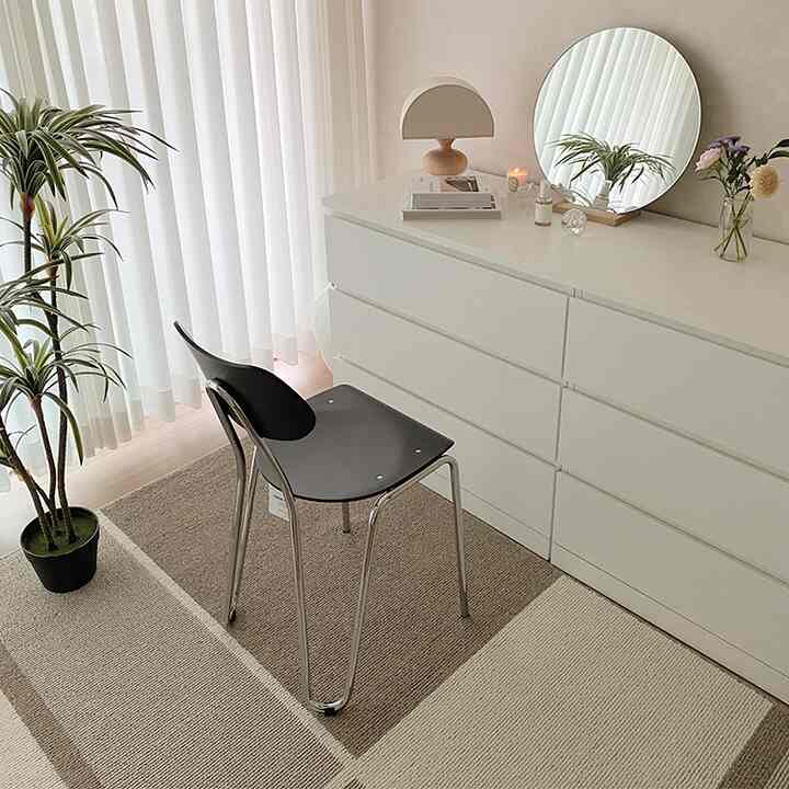 Bright white and beige toned bedroom featuring a dresser with round mirror and simple vanity setup creating a cozy space