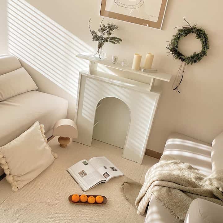 Beige-toned living room featuring a white fireplace shelf between sofas with Christmas decorations creating a cozy atmosphere