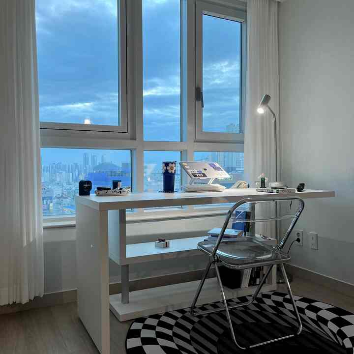 White-toned compact home office featuring a transparent folding chair and a desk in a neat workspace