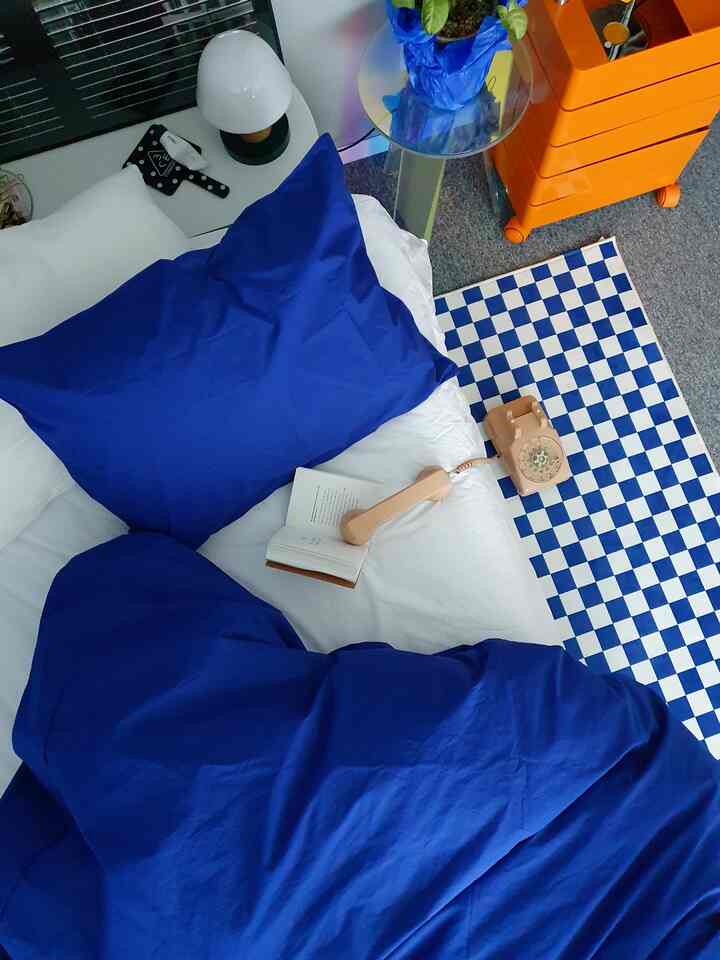 Blue and white bedding bedroom featuring vintage telephone and nightstand in a cozy setting