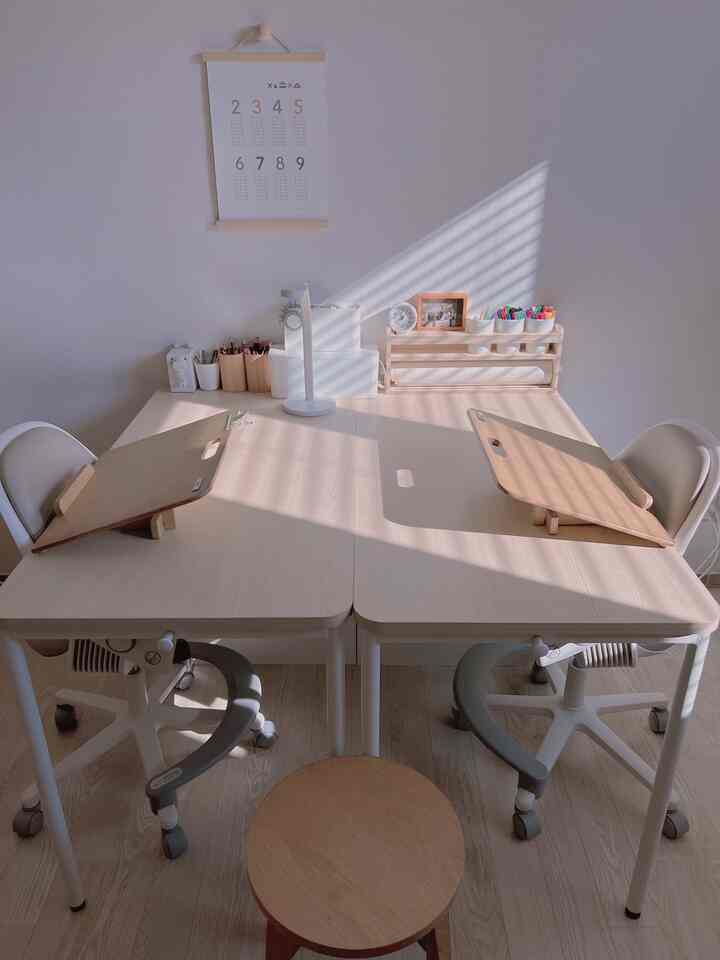 ナチュラルな木目調とホワイトの対面式子供部屋、二つの小学生用机と椅子が配置された清潔感のある空間