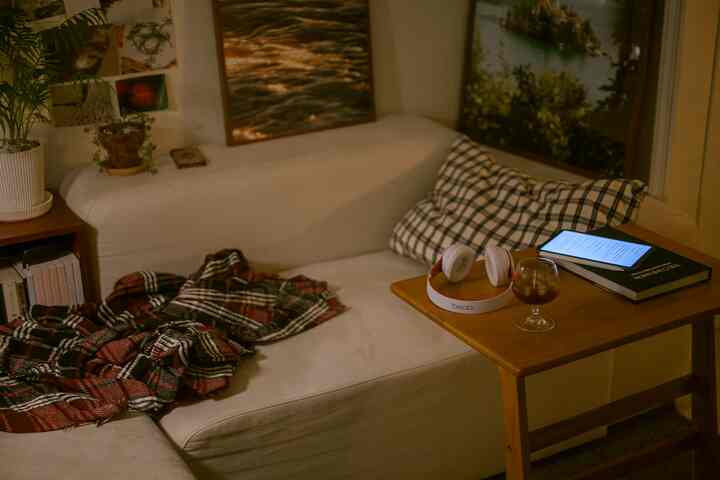 Cozy living room in warm wood tones and white, featuring a sofa and side table with an iPad and wine glass