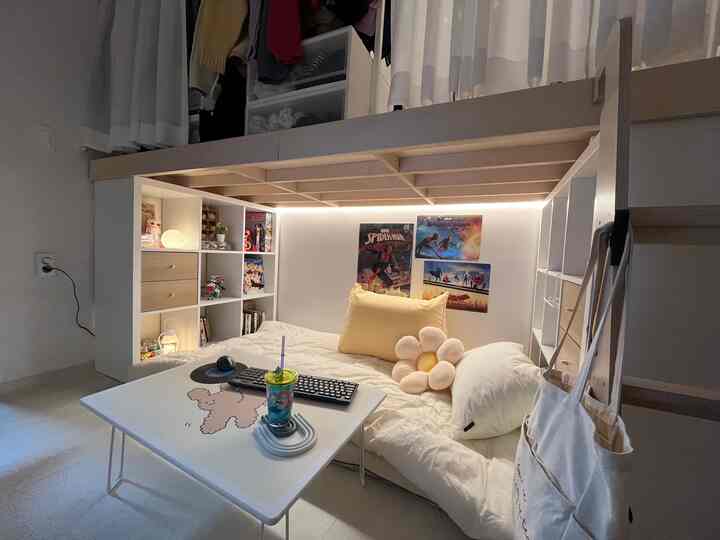 White and beige toned compact single household bedroom featuring a loft bed with cozy floor seating gaming area beneath
