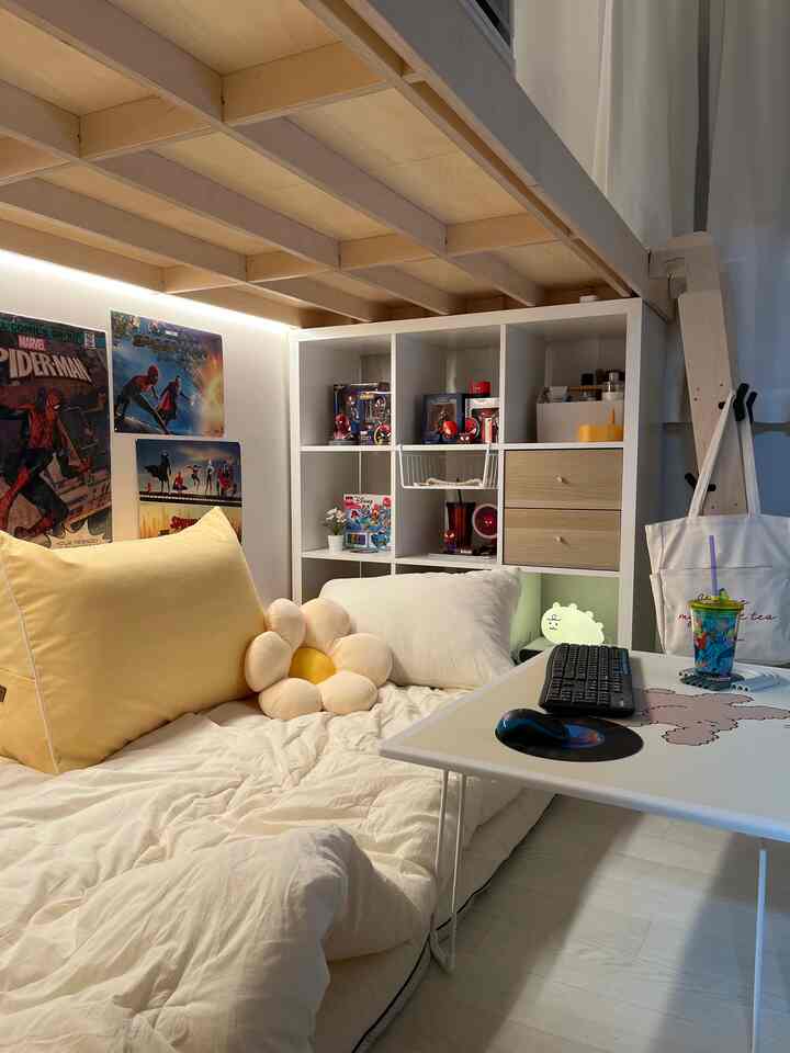 Bright wood tone and white small studio bedroom featuring cozy bedding, storage shelves, and a compact desk creating a warm atmosphere