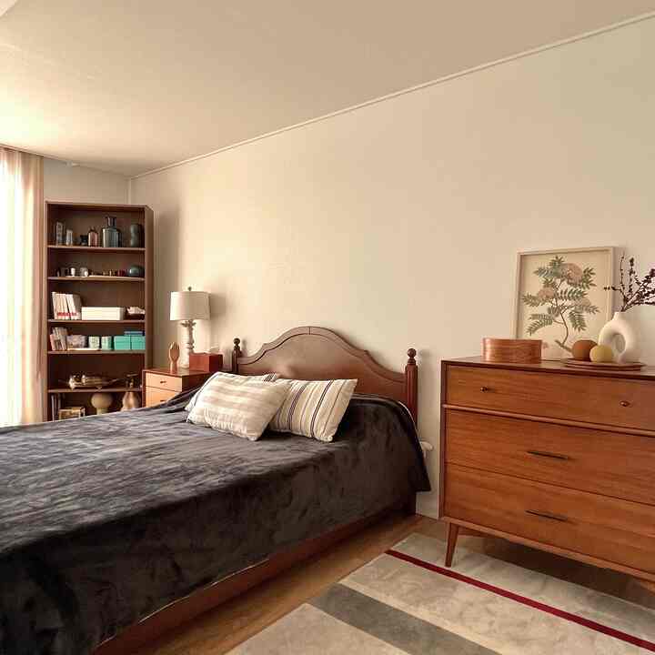 Warm brown wood tone bedroom featuring a wooden bed, dresser, and bookshelf creating a cozy atmosphere.