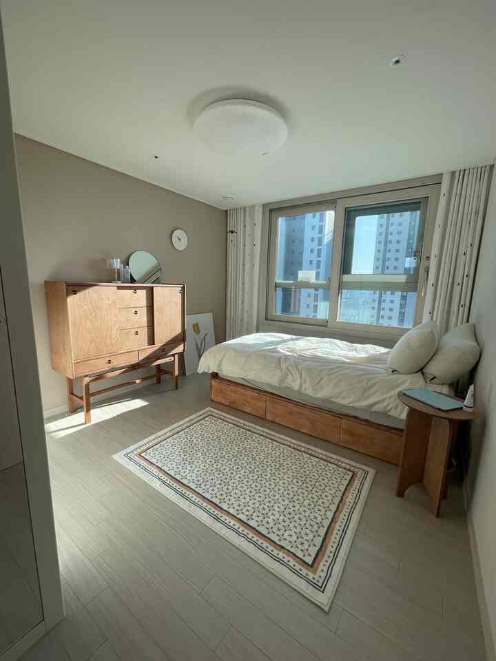 Cozy bedroom with beige walls, wood tone furniture, and white bedding arranged neatly