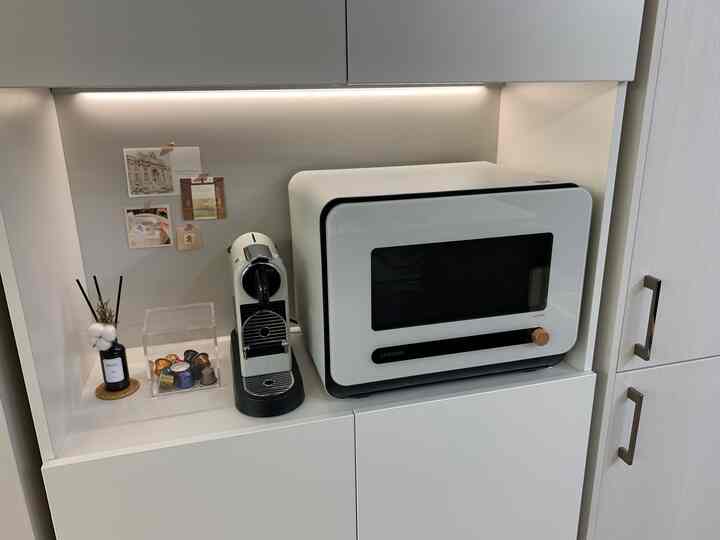 白を基調としたキッチンキャビネット内に配置されたコーヒーメーカー、電子レンジ、ディフューザーの飾りが清潔感のあるおうちカフェ空間を演出。