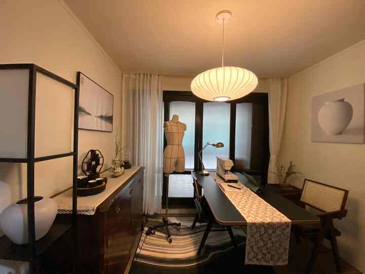 White and black toned workshop featuring a central table with a sewing machine and mannequin, creating a cozy atmosphere