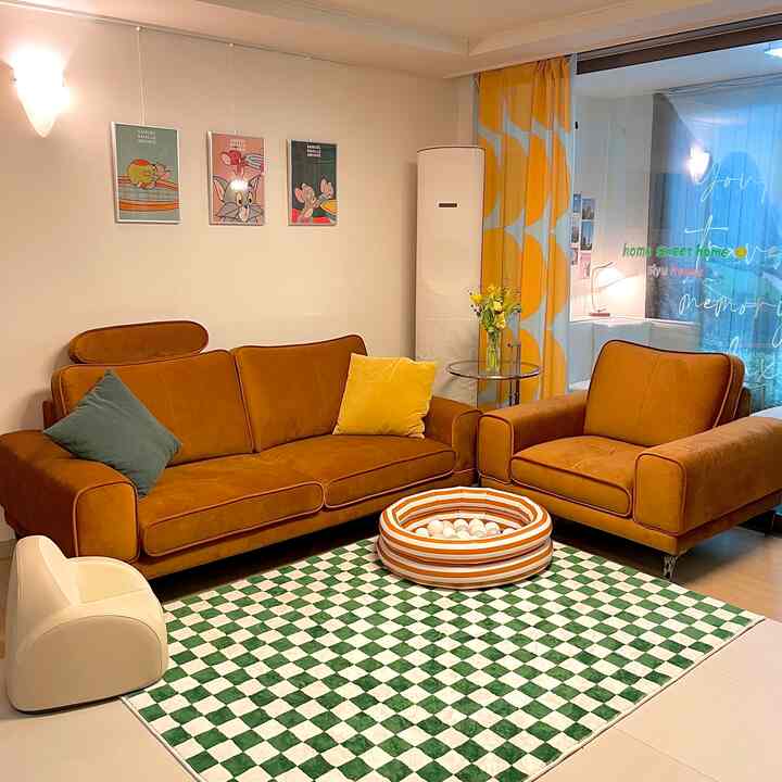 Brown-toned living room featuring large sofas, a green checkered rug, yellow patterned curtains, a circular ball pit, and a kids' chair creating a harmonious space