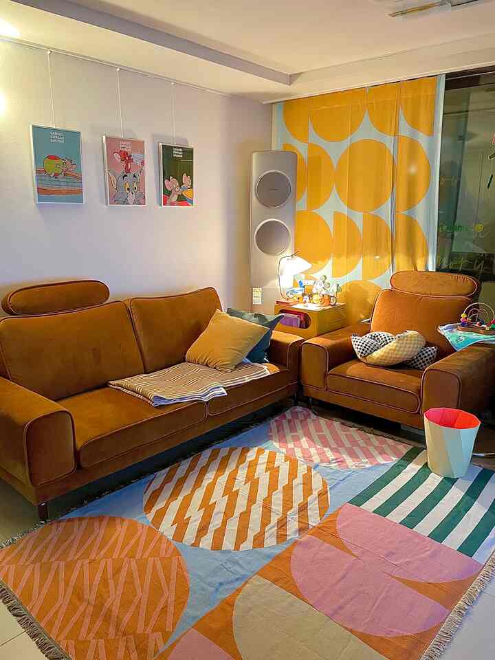 Mid-Century Modern living room with yellow and brown tones, featuring sofas, a colorful rug, and large patterned curtains creating a cozy atmosphere
