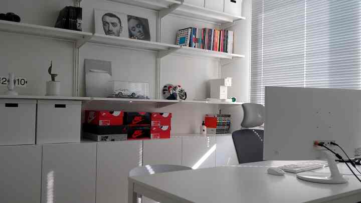 Cold white-toned study featuring custom aluminum blinds, shelves, and bookshelves in a neat home office space