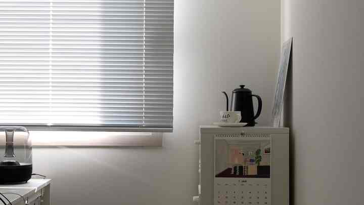 Minimal kitchen space featuring white walls and aluminum blinds with a bright and clean atmosphere