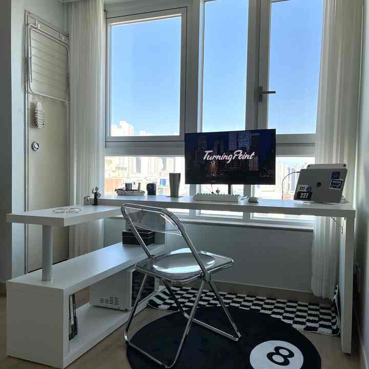 White-toned home office space featuring a transparent chair and black-and-white checkerboard rug in a modern, compact interior