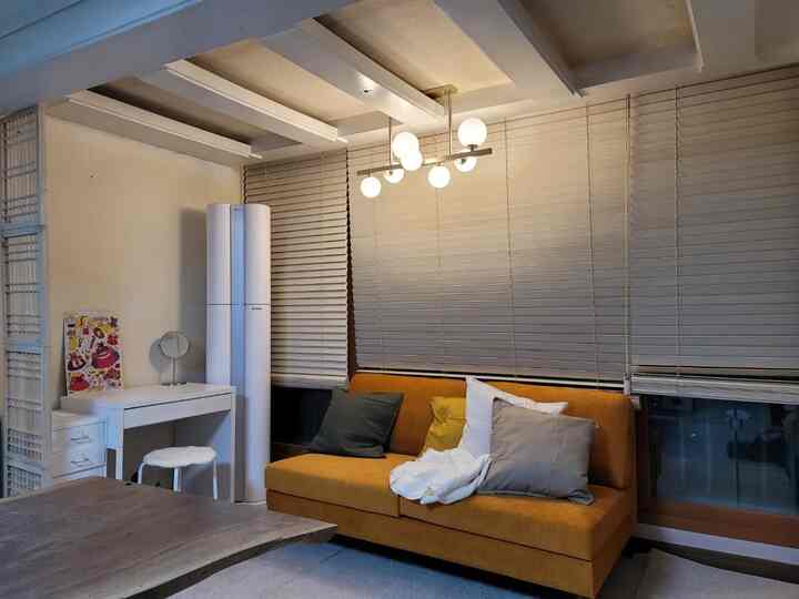 Cozy living room with beige wood blinds and orange sofa, featuring a white floor lamp for heating and air purification