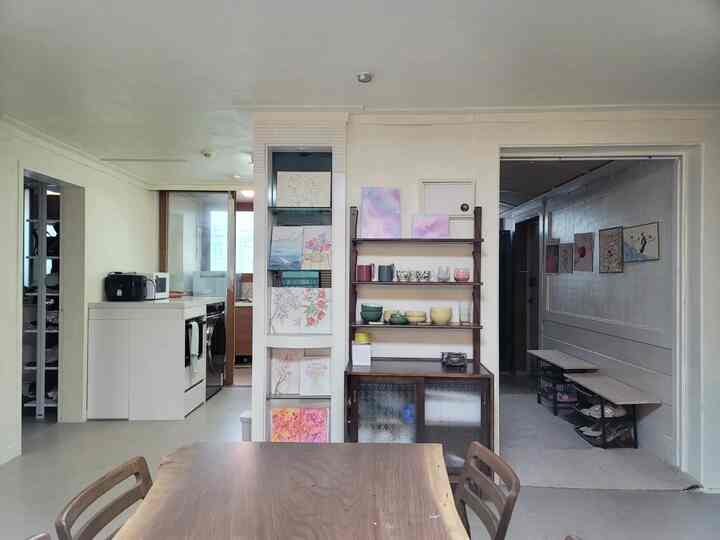 White and wood tone living room and entrance featuring various artworks and shelves in a clean, organized space
