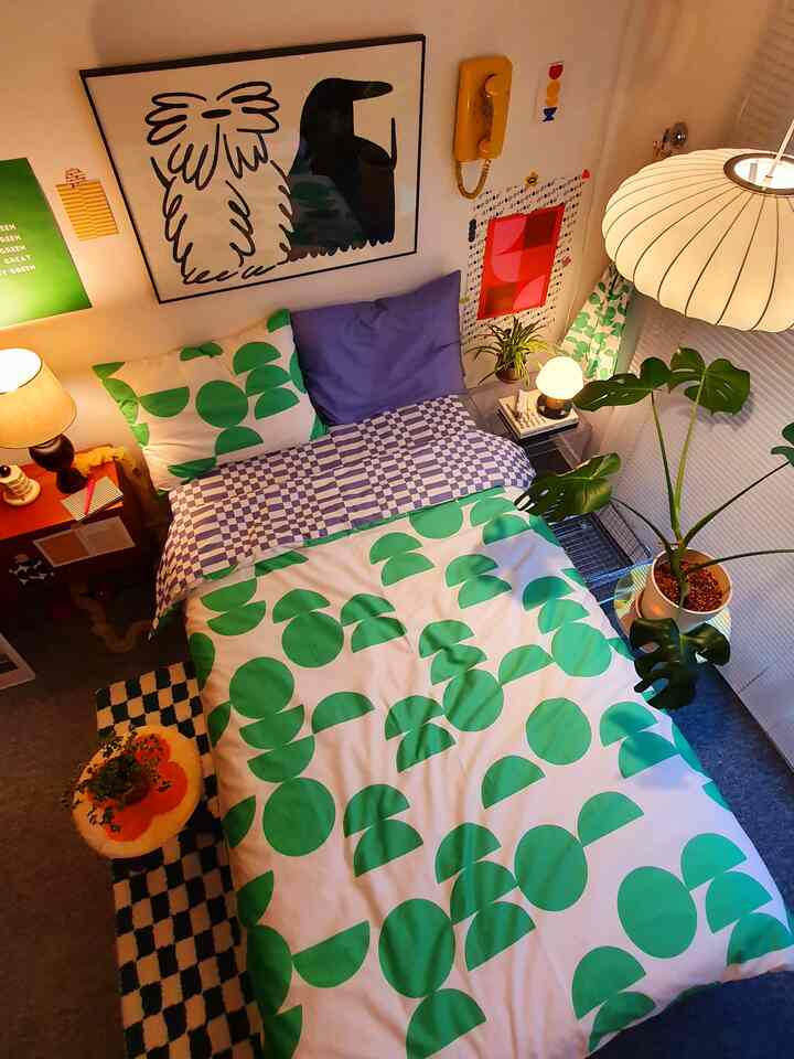 グリーンのパターン寝具と植物が調和する、ナチュラルな雰囲気の居心地のよい寝室