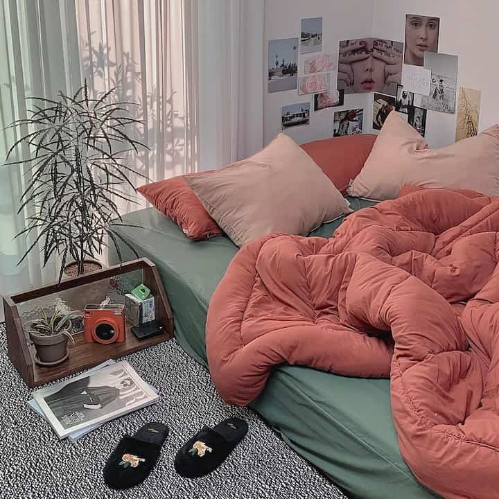 ナチュラルカラーの寝室、テラコッタの掛け布団と枕が配置された雰囲気のある空間