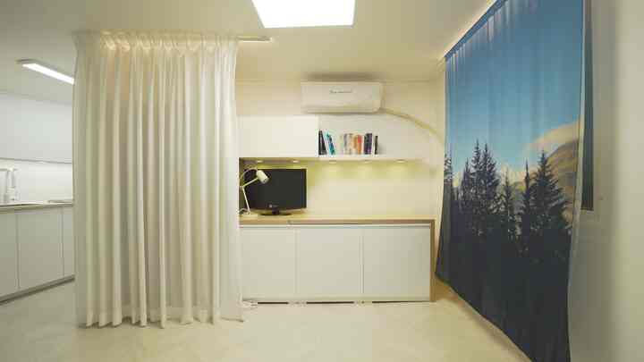 White and natural-toned home office space featuring curtains, desk, and neat storage cabinets in a compact interior
