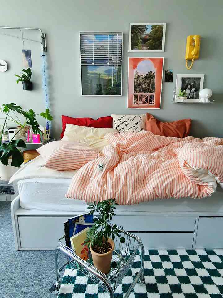 Cozy bedroom with gray walls and bright pink striped bedding featuring plants and modern furniture accents