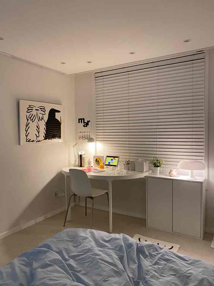 Soft white-toned bedroom home office featuring a clean white desk and ambient lighting with a cozy atmosphere