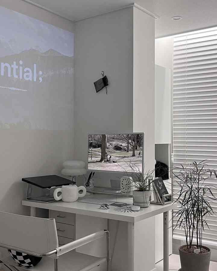 White-toned home office space featuring a modern desk and monitor stand with a clean atmosphere