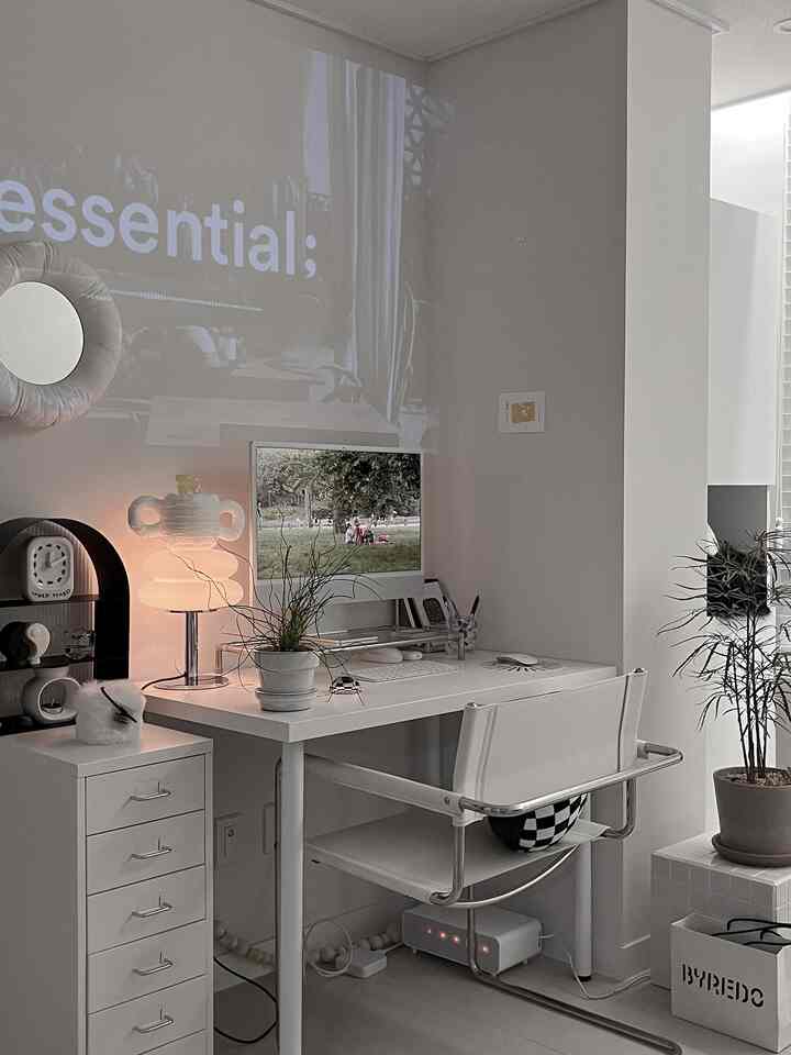 白と黒のモノトーンのホームオフィス、すっきりとしたデスクとiMac、照明が配置されたモダンなインテリア