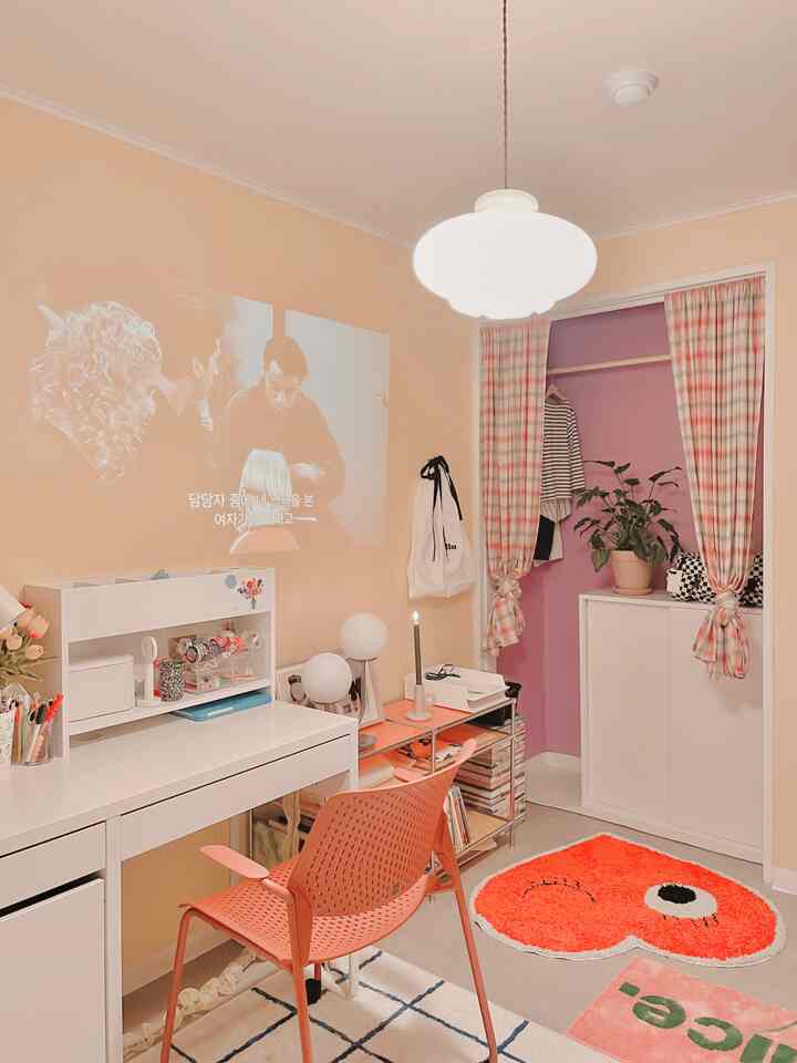 Warm beige and pink toned home office featuring a white desk, coral office chair, and a heart-shaped rug in a cozy small room