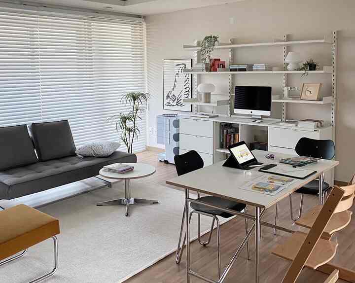 White and natural tone living room and home office featuring desks, sofa, and bookshelves creating a comfortable study and work space