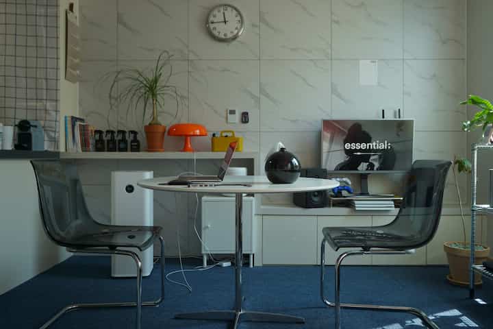 Modern studio apartment in white and light gray tones featuring transparent chairs and a round dining table