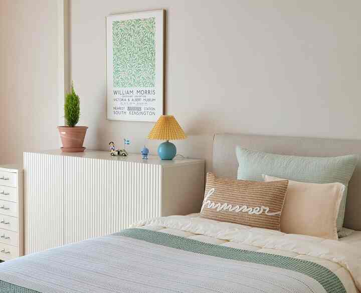 白と緑のトーンの子供部屋、ベッドと収納キャビネットが配置された自然でシンプルなインテリア