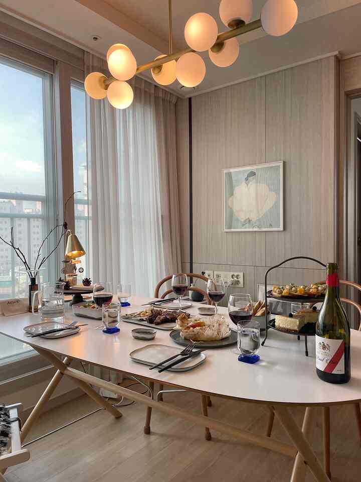 A white and wood-toned dining space featuring a table set with wine glasses and plates, creating a cozy home party atmosphere