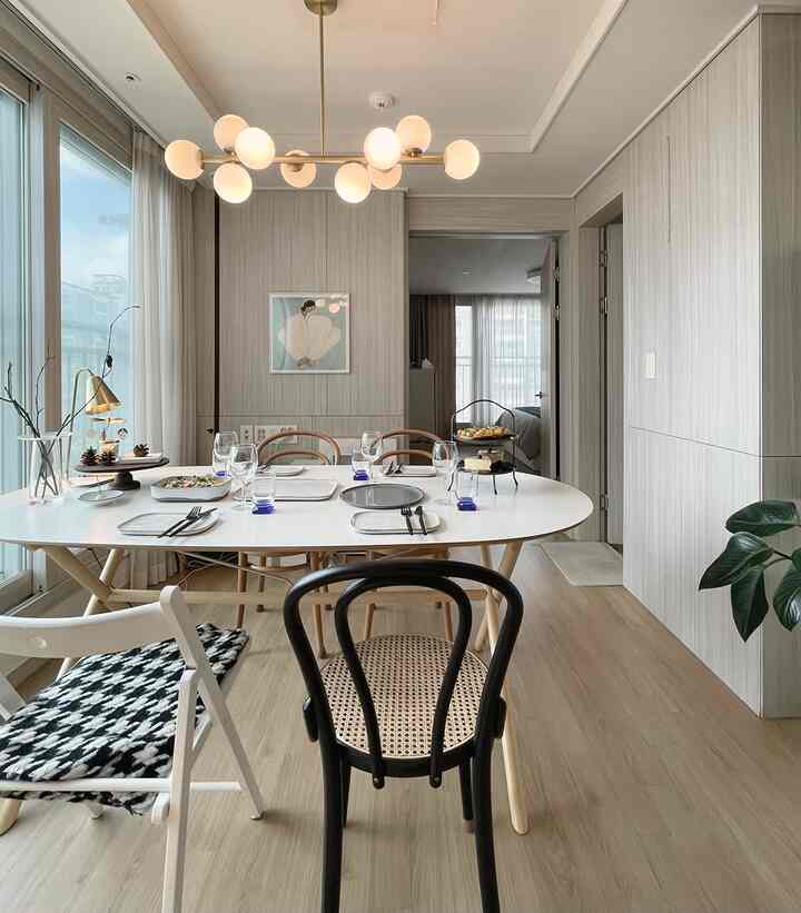 Natural tone living and dining space featuring a white dining table and wood-tone chairs creating a cozy home party atmosphere
