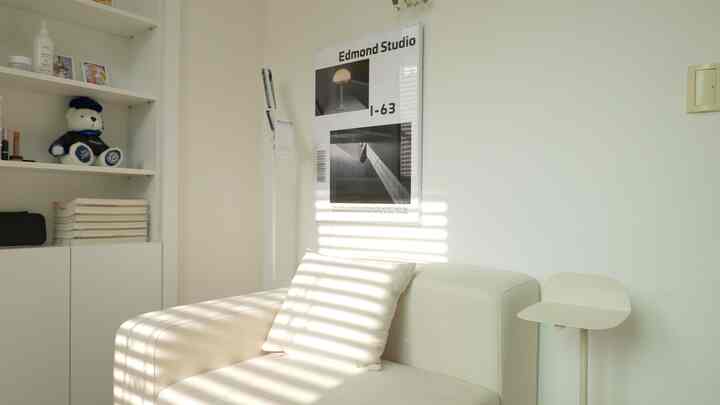 Ivory-toned living room featuring a simple sofa, side table, and picture frame with a clean, natural atmosphere
