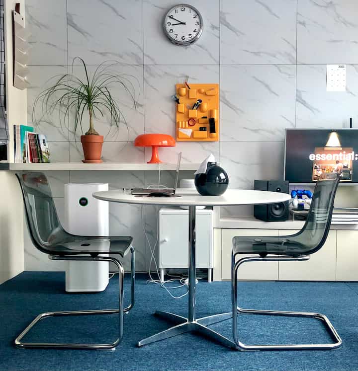 A white and blue toned studio apartment featuring a sideboard and transparent chairs with a clean modern vibe
