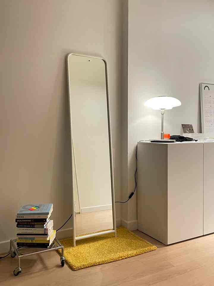 Entrance space featuring white and wood tones, with a KNAPPER full-length mirror from IKEA and a yellow rug in a simple interior