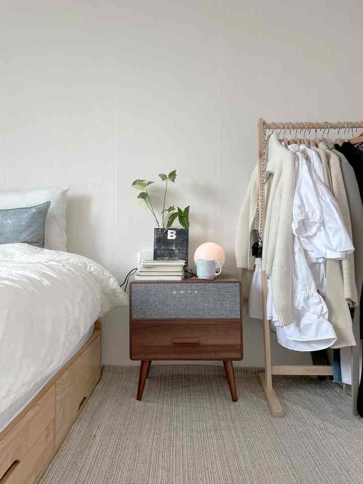 A bedroom with harmonious white and wood tones featuring a nightstand and rug, creating a neat atmosphere