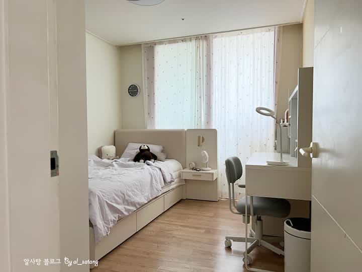 A neat small kids' room in white and wood tones featuring a storage bed, a MICKE desk, and a student chair, ideal for a middle school daughter.
