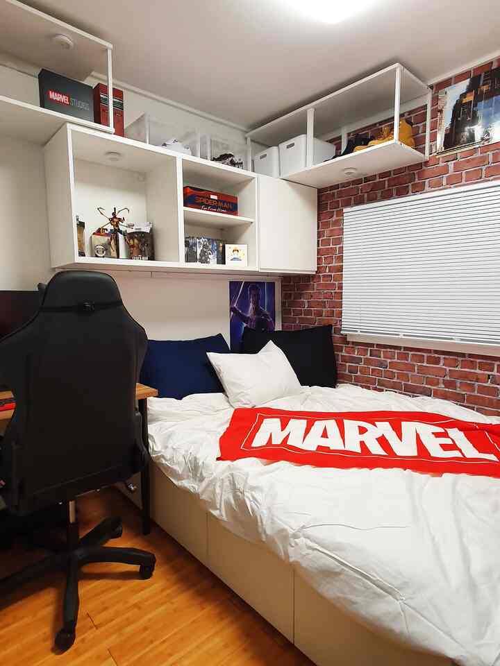 Small bedroom in white and brown tones featuring Marvel posters and a gaming chair, showcasing a minimal and modern style