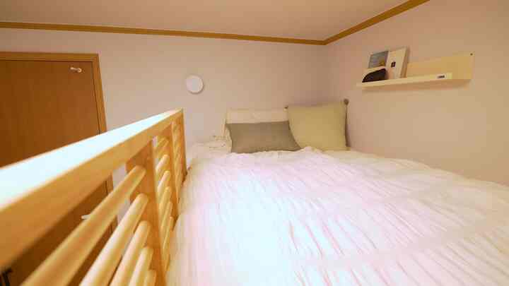 Natural tones and white bedding define a small bedroom, simple and cozy atmosphere