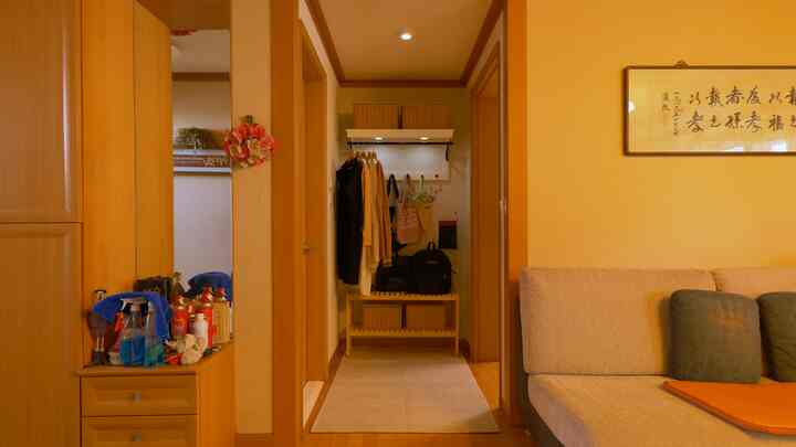 Warm wood tones and beige sofa in an entrance hallway featuring a coat rack and shelves for enhanced storage in a natural style