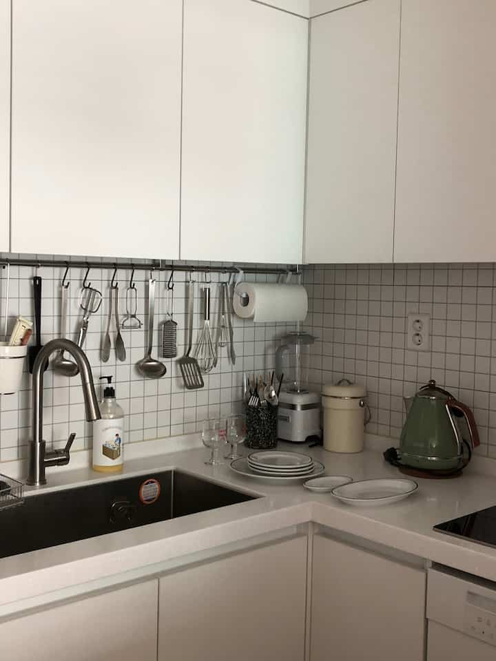 白とナチュラルカラーのキッチン、シンクや調理器具が整頓された清潔感のあるインテリア