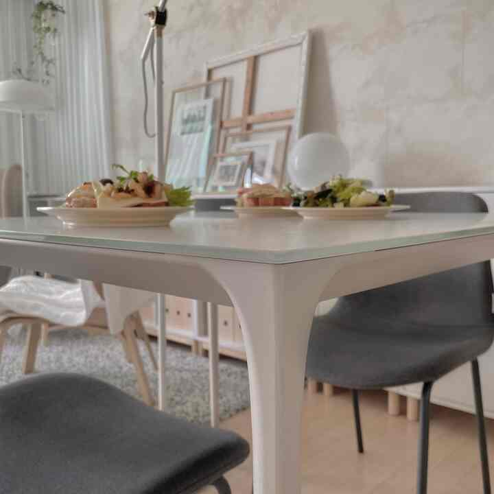 ホワイトトーンのダイニング、ガラストップのダイニングテーブルとグレーのチェアが配置されたモダンな空間