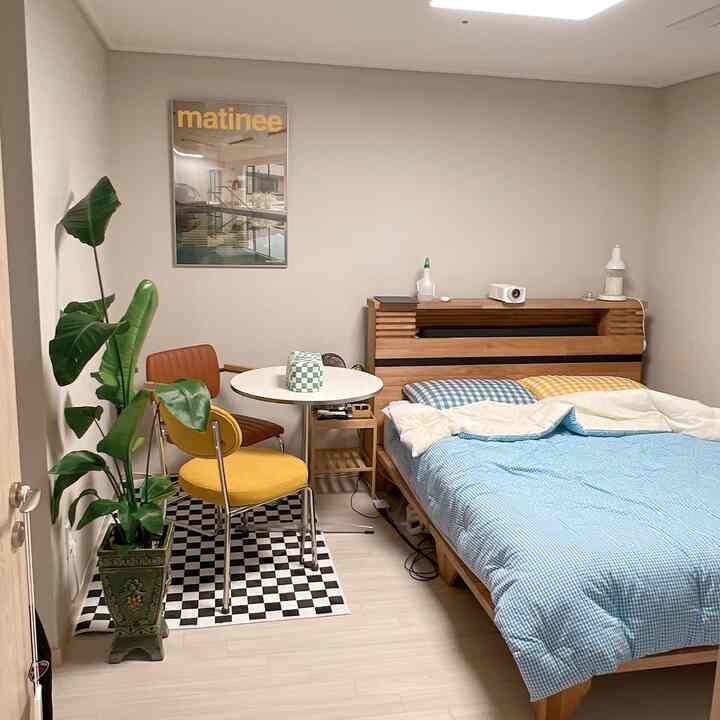 Ivory-walled mid-century modern bedroom featuring wood furniture, checkered rug, and blue-yellow check bedding creating a cozy atmosphere
