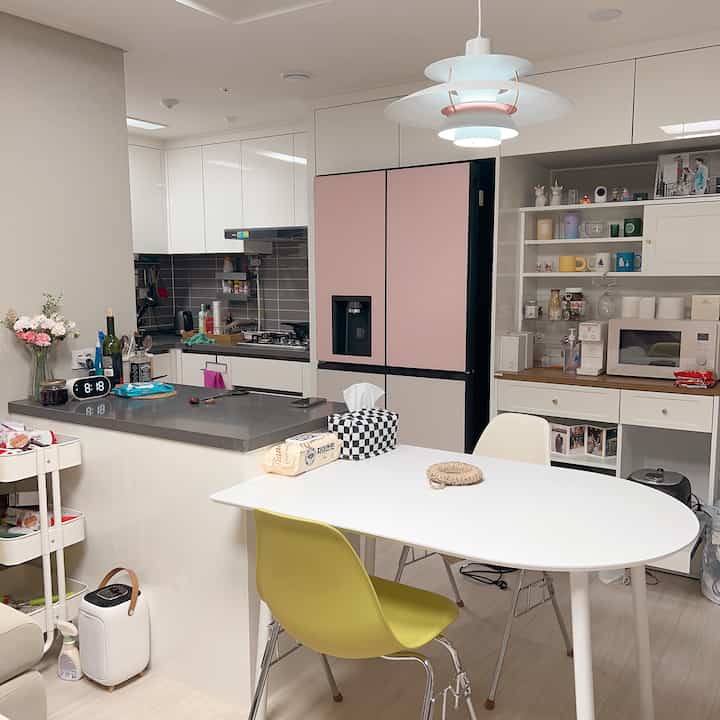 Bright white and gray toned kitchen featuring an oval dining table, practical storage, and sleek pendant lighting in a cozy newlywed space